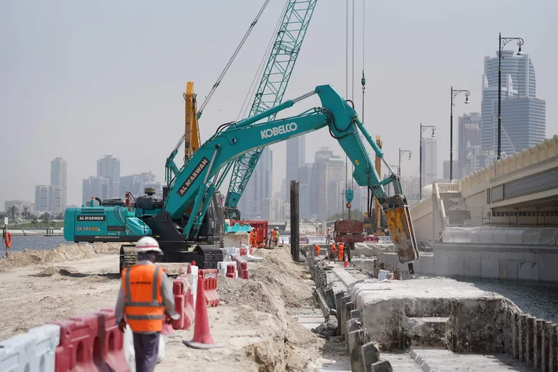 A Kobelco SK380 excavator equipped with a jackhammer for specialized tasks, working with a Komatsu PC450 digger, and a Kobelco CKS1350 crawler crane, on Al Layyah Canal project site
