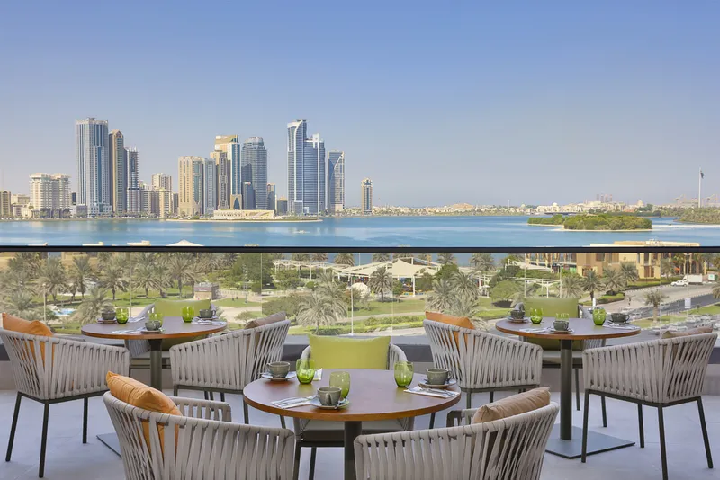 A picture showcasing the panoramic outdoor view of Al Majaz Waterfront and Khalid Lagoon offered by the cozy atmosphere of Majdolin restaurant in the DoubleTree by Hilton Hotel Sharjah