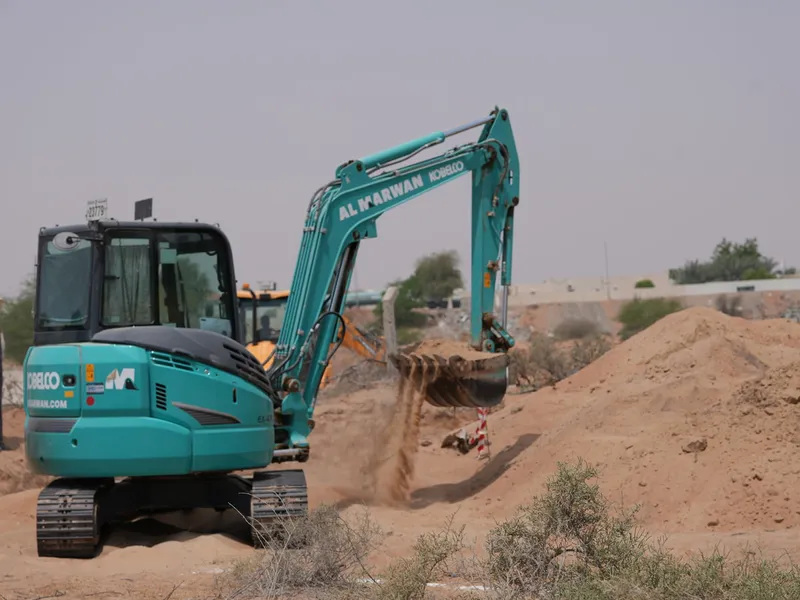 The KOBELCO SK55 mini excavator digging on an Al Marwan Machinery's rental project in the desert in Sharjah, UAE
