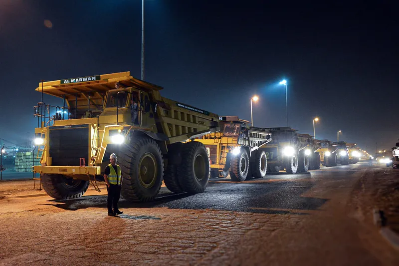 A lineup of Al Marwan's CAT and Komatsu rigid dump trucks being moved out of their Jebel Ali Free Zone (JAFZA) Yard in Dubai to be shipped