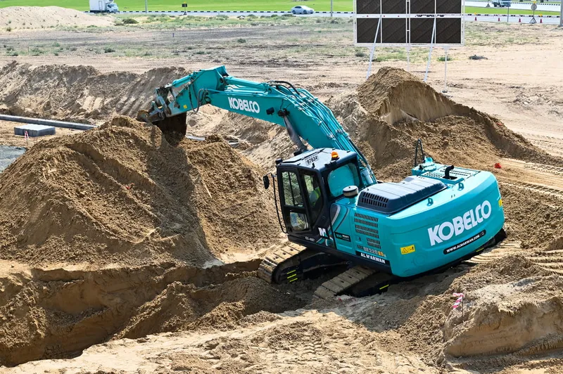 A picture showcasing the robust Kobelco excavator being used in the desert