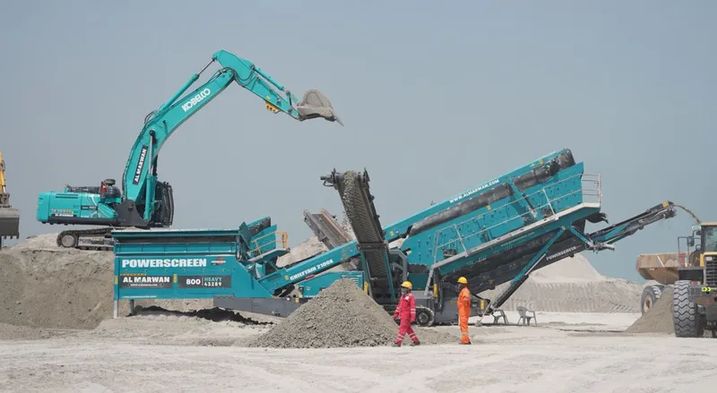 An excavator and a screener on a job site, from Al Marwan, the region's authorized distributor for brand-new Kobelco and Powerscreen equipment