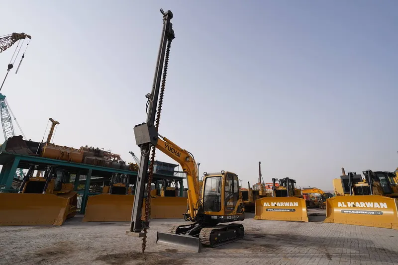 A Yuchai YC55-8 mini excavator attachment equipped with an auger for post drilling