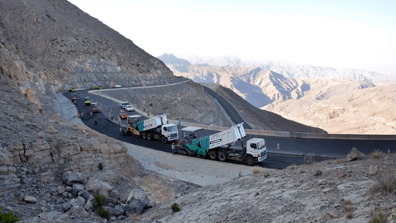 The rental fleet of Al Marwan, notably Volvo and Hino tipper trucks dropping asphalt onto Vogele asphalt-laying pavers on Jebel Jais Road