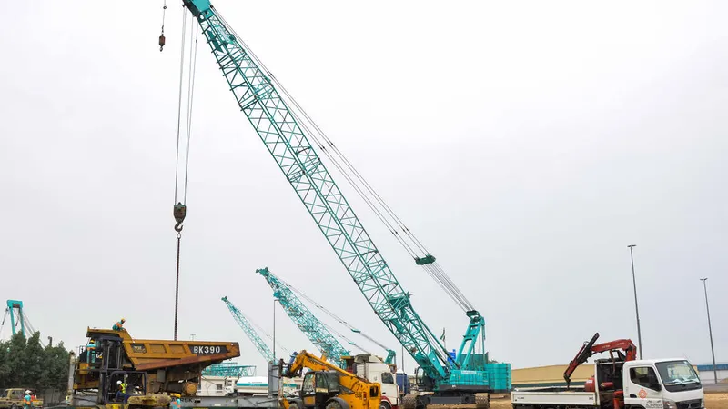 A Kobelco CKS1350 crawler crane lifting a CAT 773E dump truck into place