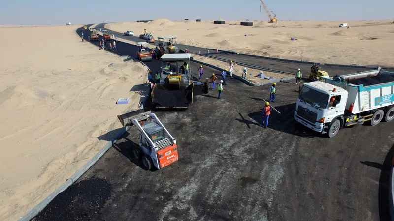 A picture of the asphalt team finishing the roadways at Tilal City using tipper trucks, pavers, rollers, and skid loaders