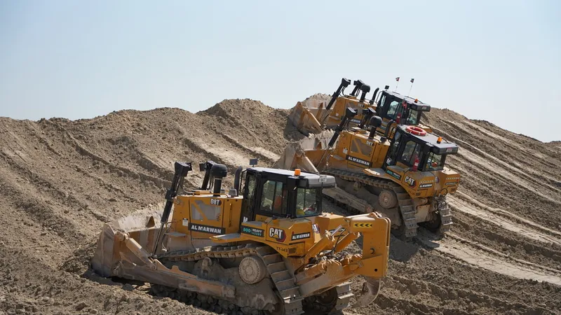 Several CAT and KOMATSU bulldozers at work on a construction site in the desert. Al Marwan Machinery heavy equipment rental fleet.