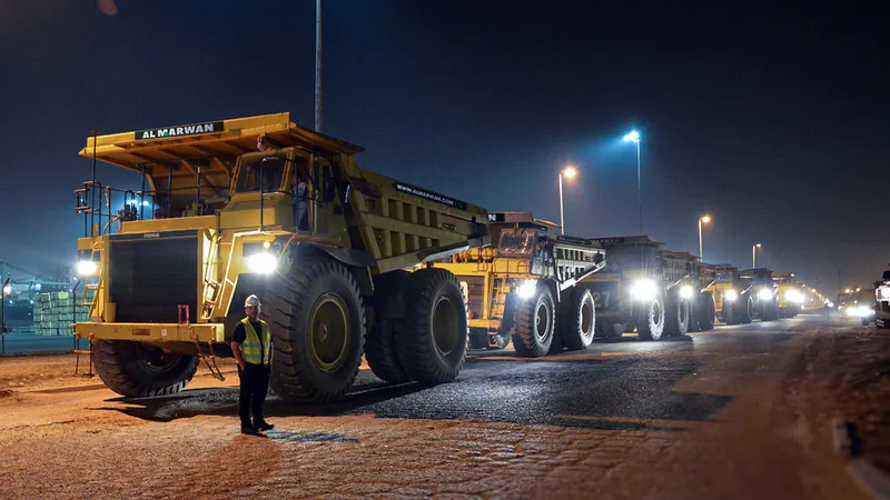 A lineup of Al Marwan's CAT and Komatsu rigid dump trucks being moved out of their Jebel Ali Free Zone (JAFZA) Yard in Dubai to be shipped