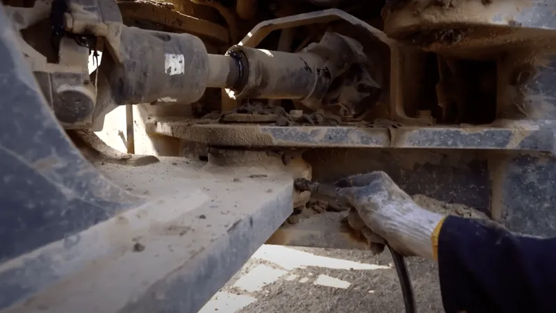 Applying grease to the articulating joint of a wheel loader