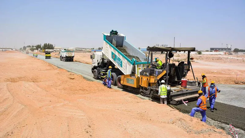 Road building equipment such as the Volvo tipper truck and the Vogele asphalt paver working on Al Jada by Arada property development project