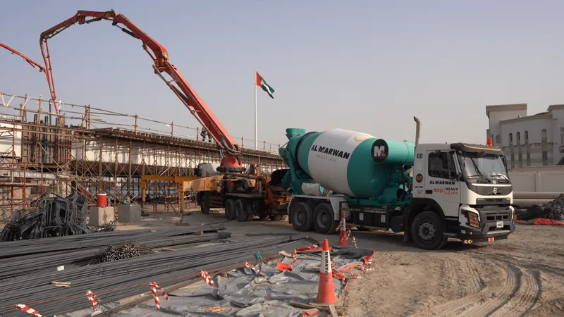 A concrete mixing truck "mixer" feeding concrete into a pump on a construction site in Sharjah, UAE