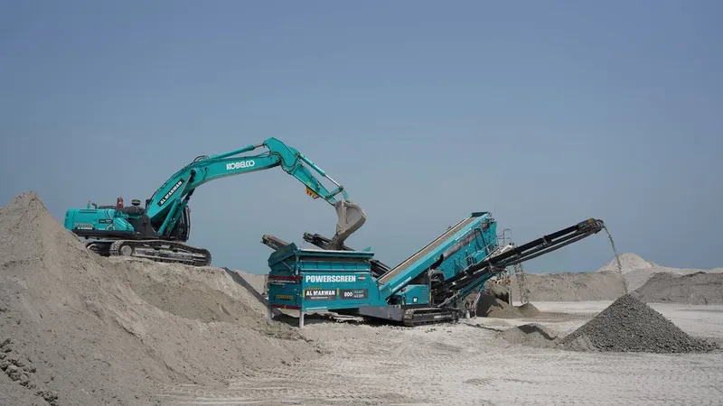 A Kobelco excavator feeding debris into the screener bar hopper