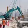 A Kobelco SK380 excavator equipped with a jackhammer for specialized tasks, working with a Komatsu PC450 digger, and a Kobelco CKS1350 crawler crane, on Al Layyah Canal project site