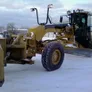 Motor grader attached to a front snow plow