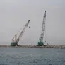 A pair of KOBELCO hydraulic crawler cranes helping reinforce marine barriers on a construction site in Oman