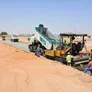 Road building equipment such as the Volvo tipper truck and the Vogele asphalt paver working on Al Jada by Arada property development project