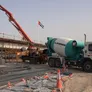 A concrete mixing truck "mixer" feeding concrete into a pump on a construction site in Sharjah, UAE