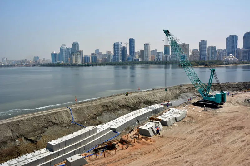 A picture of the Kobelco 7250S hydraulic crawler crane lifting marine barriers to create the edge wall on Al Majaz Island