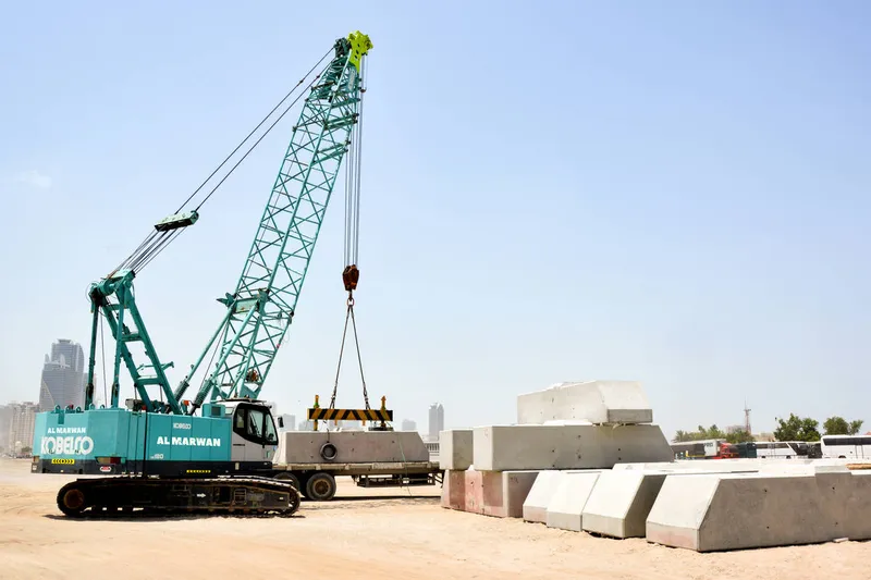 رافعة كوبلكو المجنزرة الهيدروليكية موديل CKS800 أثناء رفعها للحواجز الخرسانية في الشارقة، الإمارات.